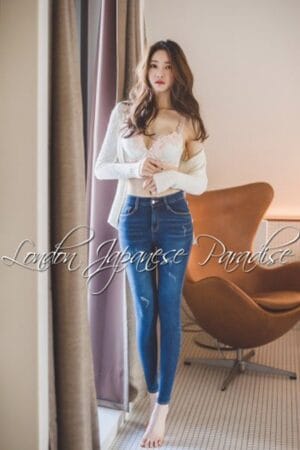 Lucy Taiwanese London Agency Escort poses by the window in tight blue jeans