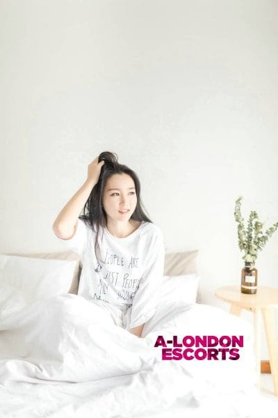 Winnie Asian Cannon Street Escort in tshirt sat in her bed