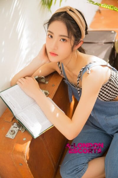 Eko Japanese Teen Escort reading a book on top of a suitcase