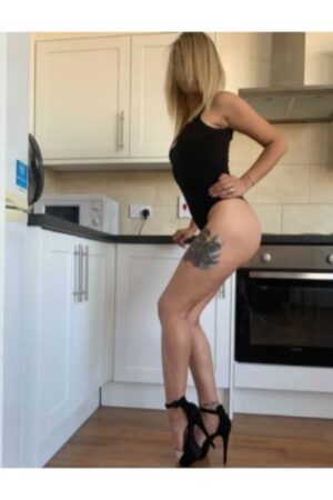 blonde Inverness escort poses in black bodysuit