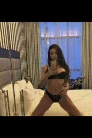 young brunette Milton Keynes escort takes selfie knelt on the bed