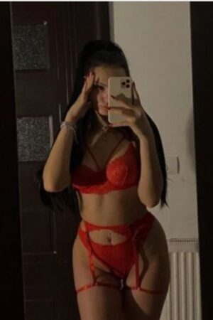 curvy brunette Cambridge escort in red takes a selfie