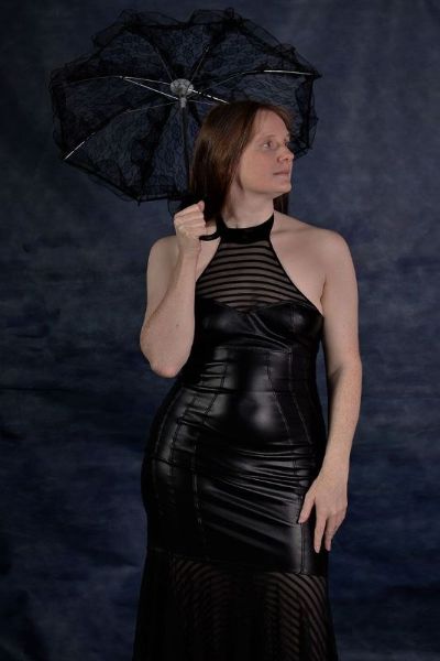 Auburn Delight in a dark black dress holding an umbrella