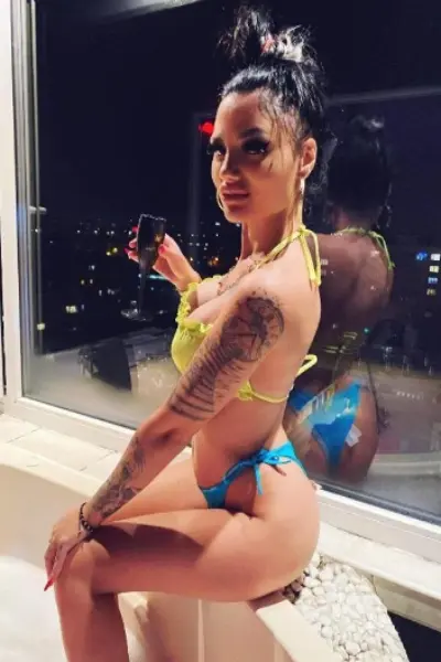 Busty tattooed escort drinking in a hot tub