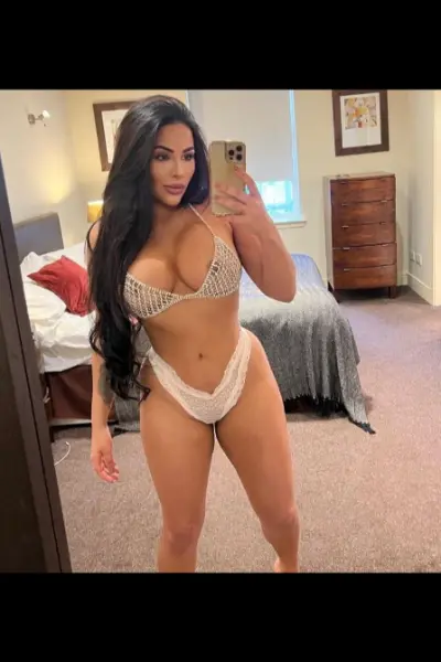 Busty dark haired escort in a bikini taking a selfie