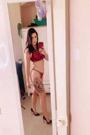 Sexy tattooed escort in red lingerie
