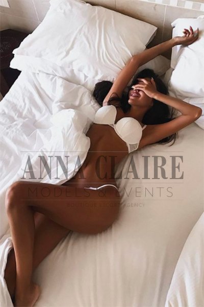 Sexy tanned escort laid in bed