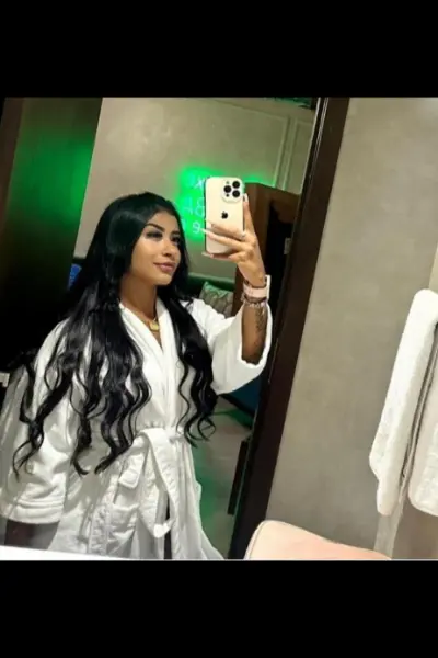 Escort in a white robe taking a selfie