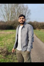 Asian male escort in grey coat holding sunglasses