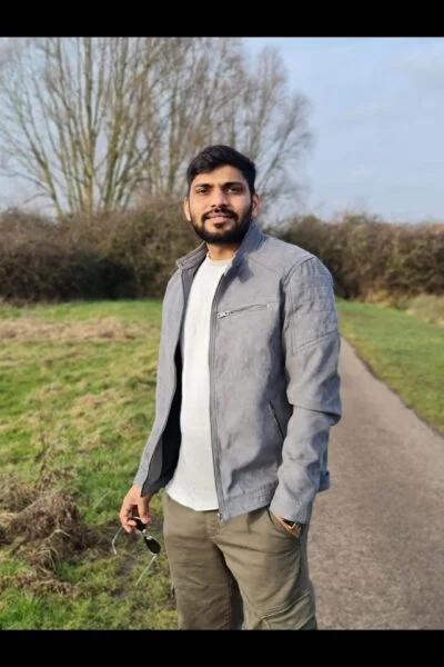 Asian male escort in grey coat holding sunglasses