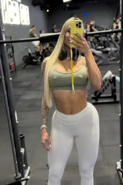 Blonde escort taking a picture in the gym