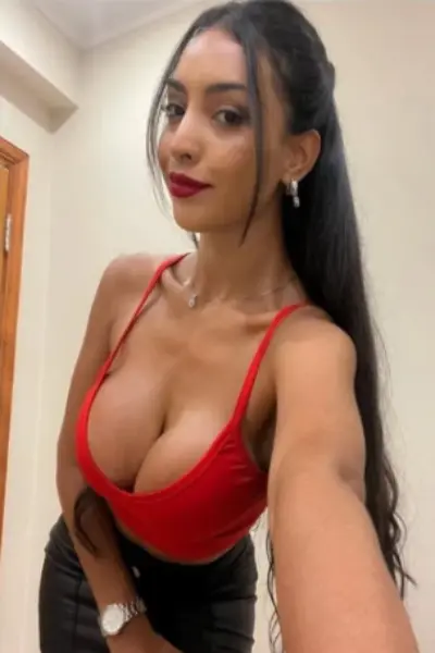Busty Cuban escort in tight fitting red vest